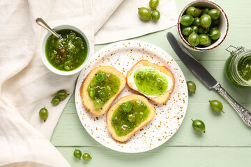Plate of tasty sandwiches with gooseberry jam on green wooden background