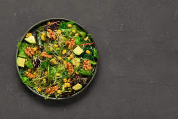 Plate with fresh salad on black background