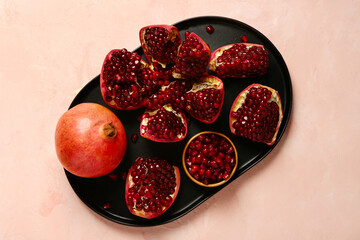Plate with fresh pomegranates on pink background