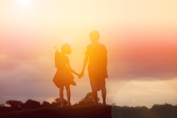 Fototapeta premium a silhouette of a happy young girl child the arms of his loving mother for a hug, in front of the sunset in the sky on a summer day.