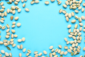 Frame made of tasty pistachio nuts on blue background