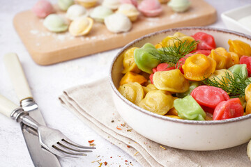 Bowl of boiled colorful dumplings with dill on white background