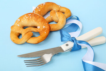 Soft pretzels and ribbons in color of Bavarian flag on blue background