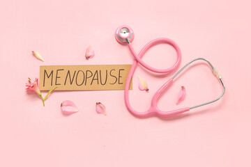 Word MENOPAUSE with petals and stethoscope on pink background