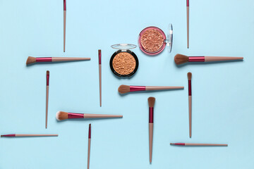 Makeup brushes and different decorative cosmetics on blue background