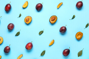 Fresh ripe plums and leaves on blue background