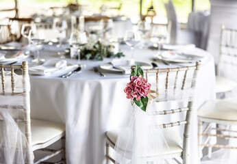 A wedding table covered with a white tablecloth, decorated with flowers, candles, glasses and cutlery.
