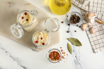 Board with jars of delicious sauerkraut and different spices on white background