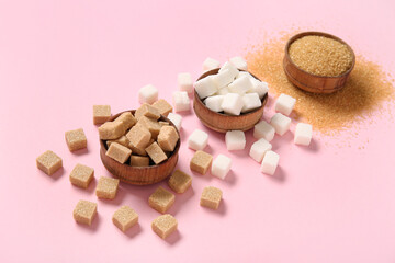 Bowls with different types of sugar on pink background