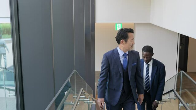 ビルの中を歩きながら会話する多国籍ビジネスパーソンのグループ