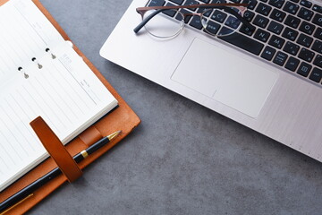 リング式のシステム手帳を開いて、ノートパソコンでデスクワークをしているイメージ
