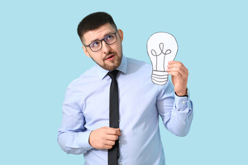 Young businessman with drawn light bulb on blue background. Business idea concept