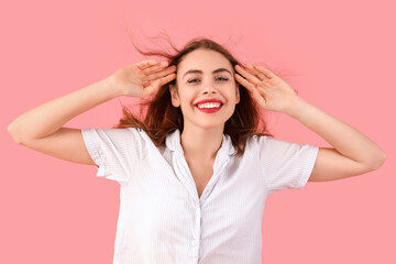 Fototapeta premium Portrait of happy young woman in pajamas on pink background