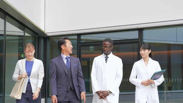 A group of multinational business people and engineers in white coats walking and talking