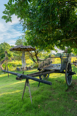 A wooden cart used for carrying goods, which was placed on the backs of oxen in the past, is placed under a tree near a roadside rest area, looking naturally beautiful.