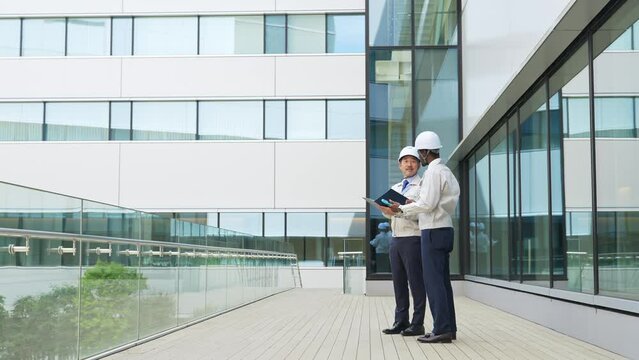 ビルの前で会話する多国籍エンジニアのグループ