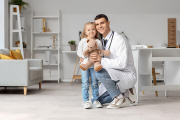 Male pediatrician and little girl with teddy bear in clinic