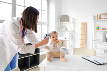 Female pediatrician measuring temperature of little baby in clinic