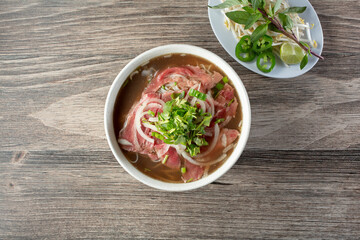 A top down view of a bowl of rare wagyu beef pho.