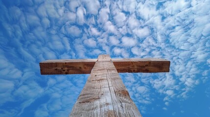 Fototapeta premium Cross made of wood, viewed from below against a blue sky with scattered clouds, evokes faith and spirituality, serene ambiance