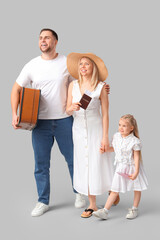 Happy family with suitcase and passport on grey background