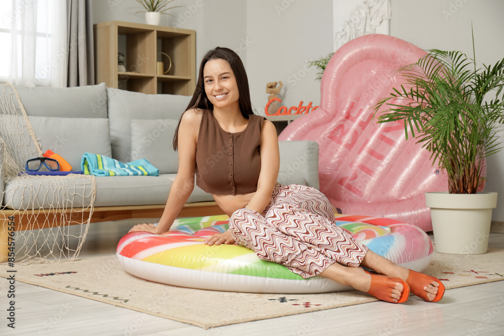 Wall mural Young pretty woman lying on inflatable ring in living room