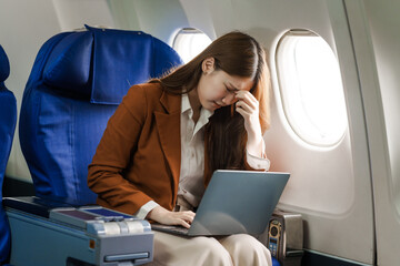 A young Asian woman is sitting in her seat as an airplane passenger, experiencing airsickness with...