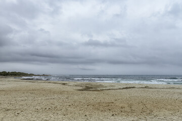 Distant Sailboat on Overcast Day at Punta Prima Beach