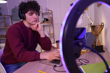 Fototapeta premium Male student studying while streaming at home in evening