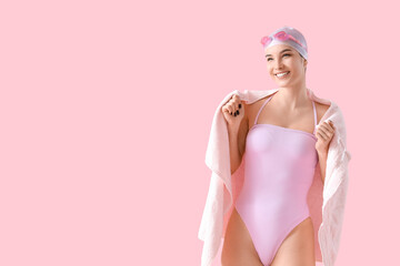 Female swimmer with towel on pink background