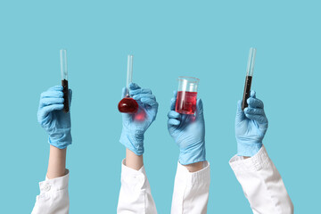 Scientist's hands holding test tubes with soil and red liquids on blue background