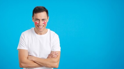 Man standing with english flag painted on face smiling