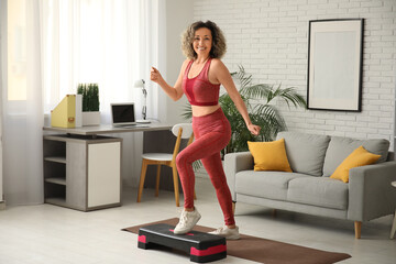 Happy mature sporty woman training with stepper at home