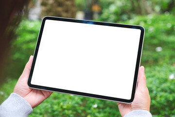 Mockup image of a woman holding digital tablet with blank white desktop screen in the outdoors