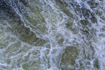 Close up detail of fierce white water river rapids from a clean deep green colored river forming a textured background