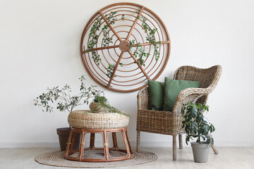 Wicker armchair with soft cushions, houseplants and wooden decor near white wall