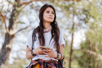 Beautiful woman using mobile application to navigate in autumn forest