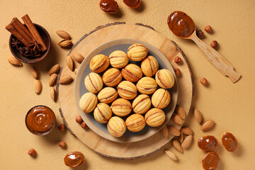 Tasty walnut shaped cookies with boiled condensed milk, almonds, hazelnuts and cinnamon on beige table