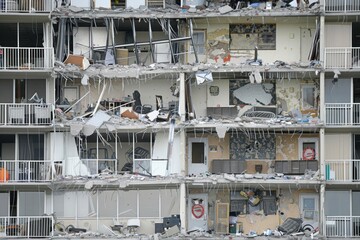 Close-up of a building with severely damaged floors, exposing interiors, debris, and broken furniture, highlighting the aftermath of a destructive event.