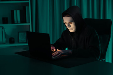 White criminal anonymous mask installing coding password encryption by programming hack, trying to make insecure thorough privacy taking massive database on computer for ransom to company. Pecuniary.