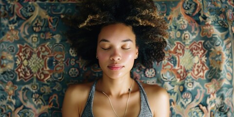 A woman sits with her eyes closed, looking down in contemplation