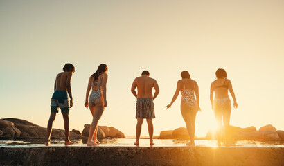 Group of friends enjoying a summer day at the beach during sunset