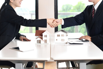 建築模型の前で握手する男女のビジネスマン