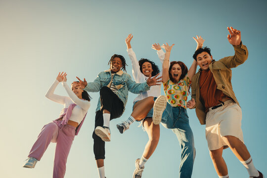 Group of friends jumping and having fun outdoors in the sunshine