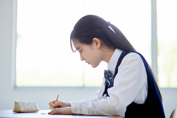 学校の教室で授業を受ける制服を着た高校生の女性