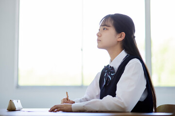 学校の教室で授業を受ける制服を着た高校生の女性