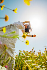 Summer mood. a young and cheerful girl posing against a background of blue sky and flowers. A...