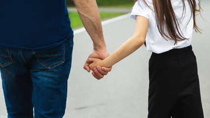 Father and daughter ride on roller skates. Girl learning to roller skate, and falls. Dad teaches daughter to ride on rollers