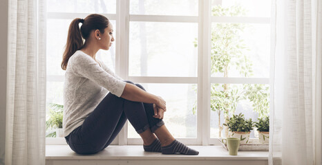 Woman sitting next to a window and looking away