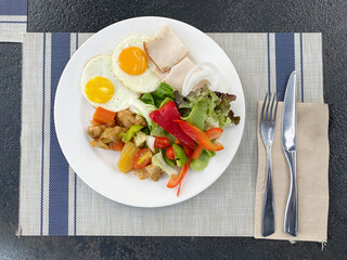 Breakfast salad with fried eggs and ham on the table